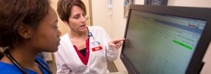 Nursing instructor with female nursing student reviewing information on computer screen.
