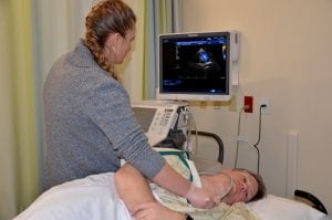 Sonography instructor performs echo on patient.
