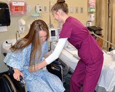 Nursing Assistant helping female patient into wheelchair