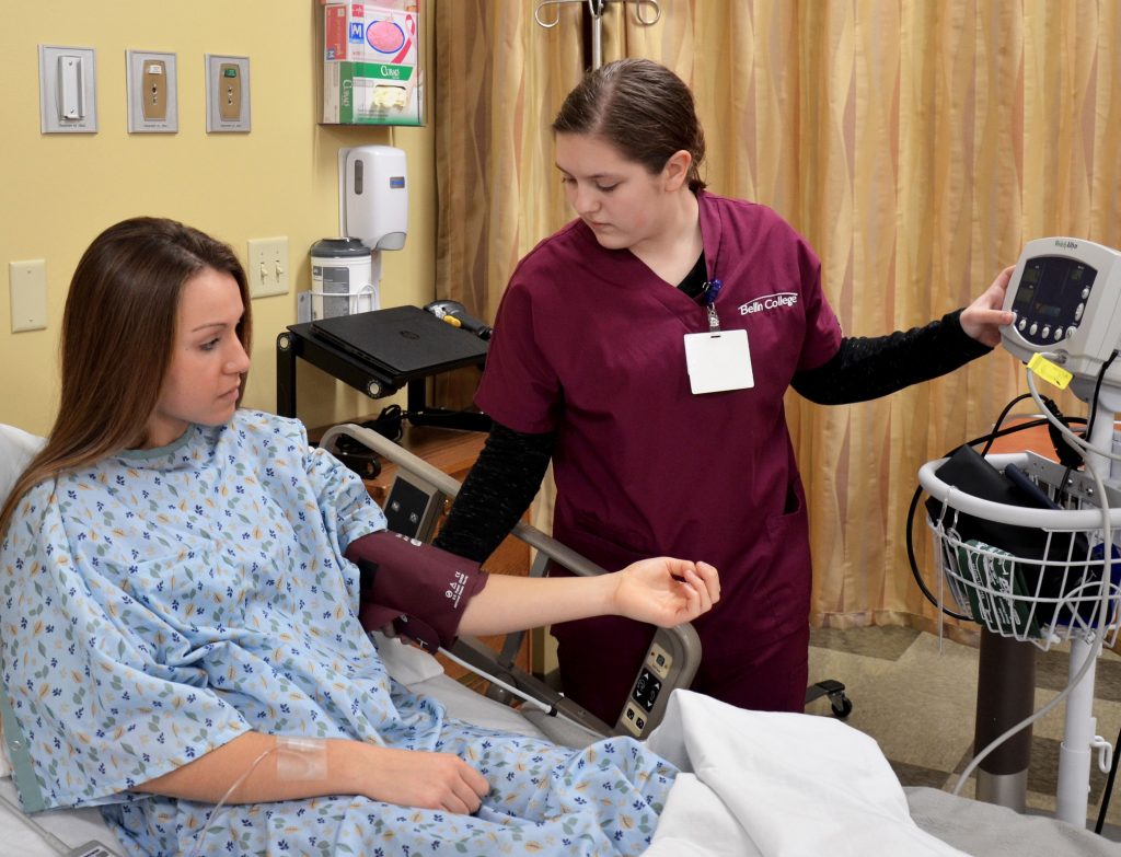 Student taking blood pressure of young female patient.