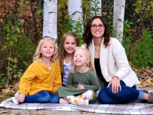 Woman sits on blanket with three children.