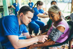 Student takes blood pressure of resident in Guatemala.