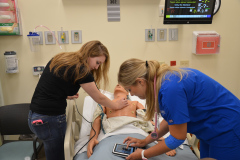 Two students practicing taking vitals with manikin simulator technology