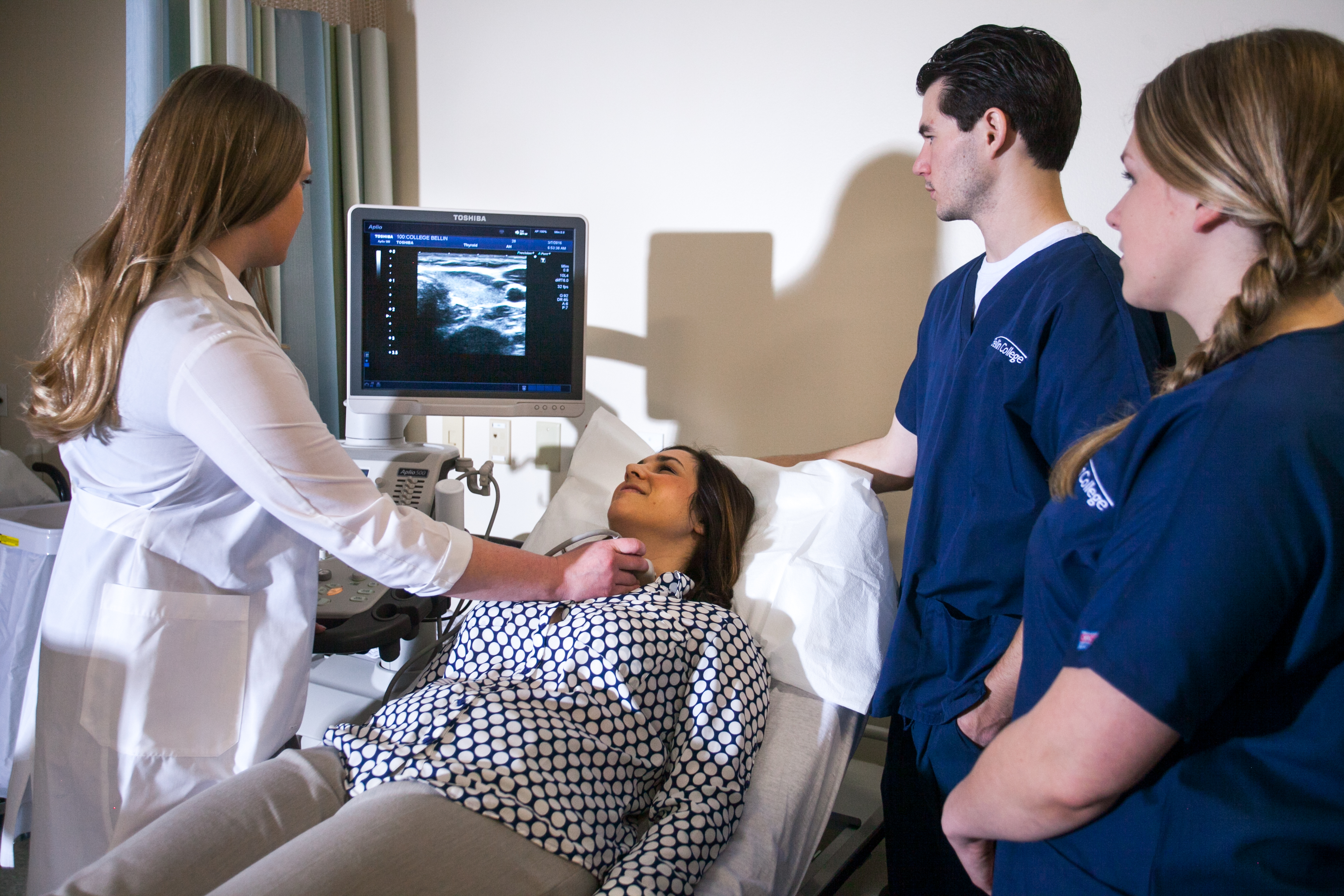 Neck scan using ultrasound machine as students look on